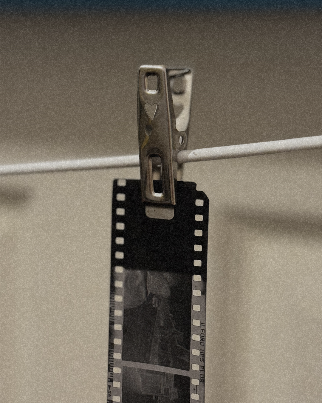 Black and white film strip clipped to a clothesline, featuring Ilford HP5 Plus black and white film, ideal for film photography, analog photography, and vintage camera content.