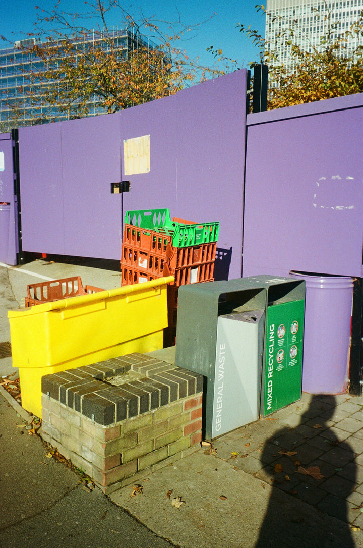Collage of various objects including a purple box, green and red crates, and a yellow object on a textured surface, shot on lomography color negative 400