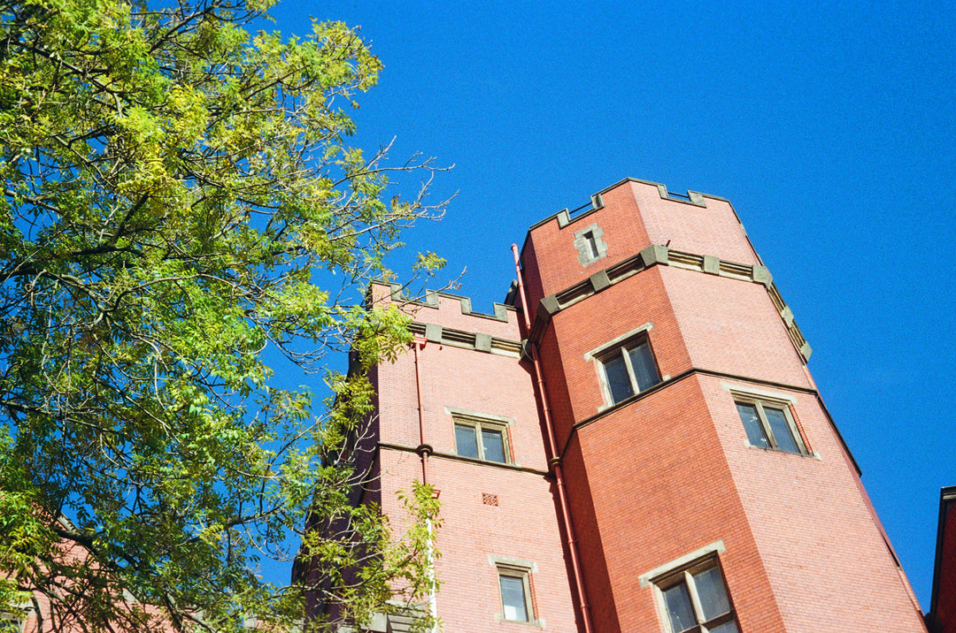 Brick tower of Firth Court with decorative elements against a clear blue sky, lomography color negative 400