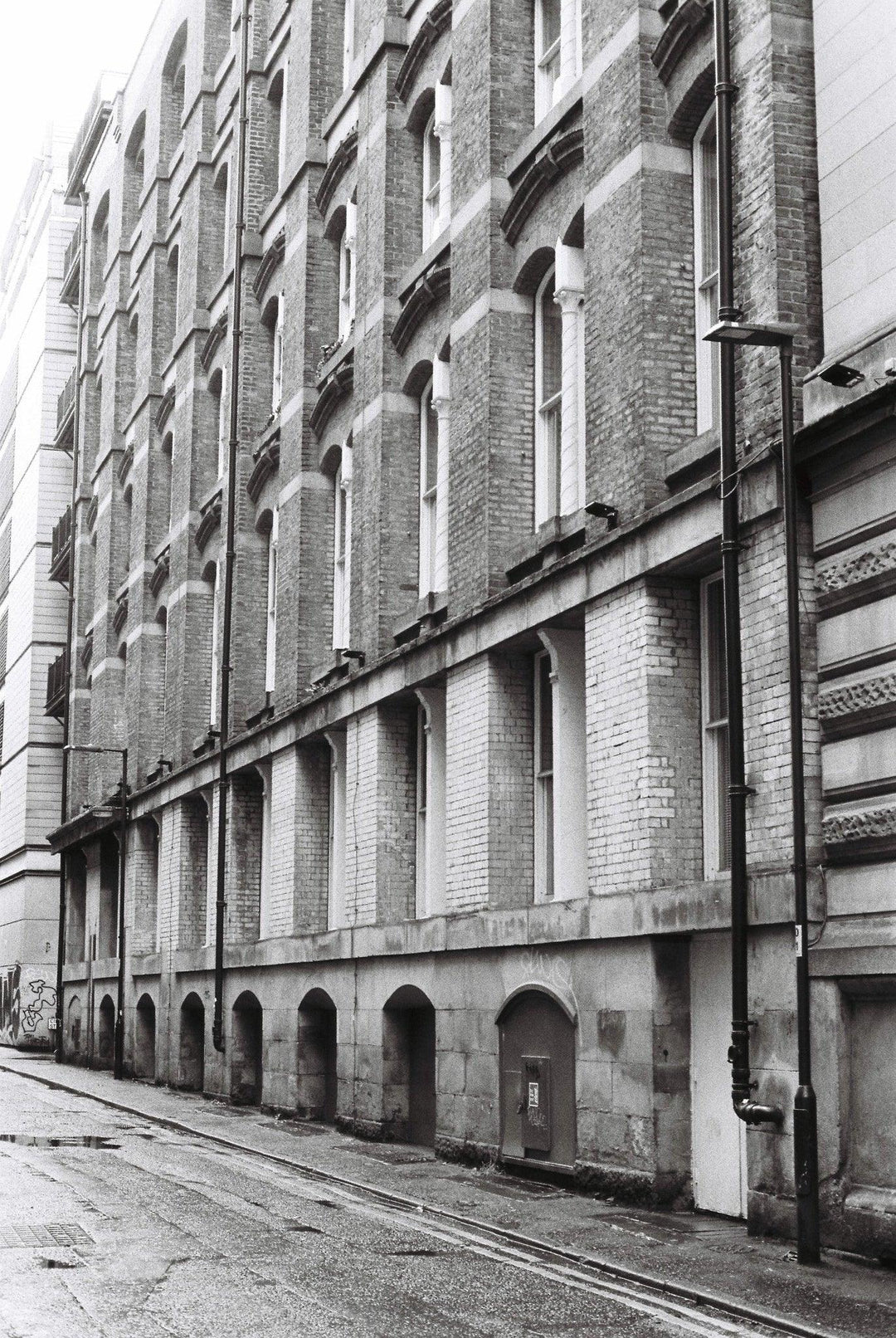 Street near a historical building in Manchester photographed on Ilford HP5 400 Plus film, featuring smooth mid-tones, deep blacks, and fine detail.