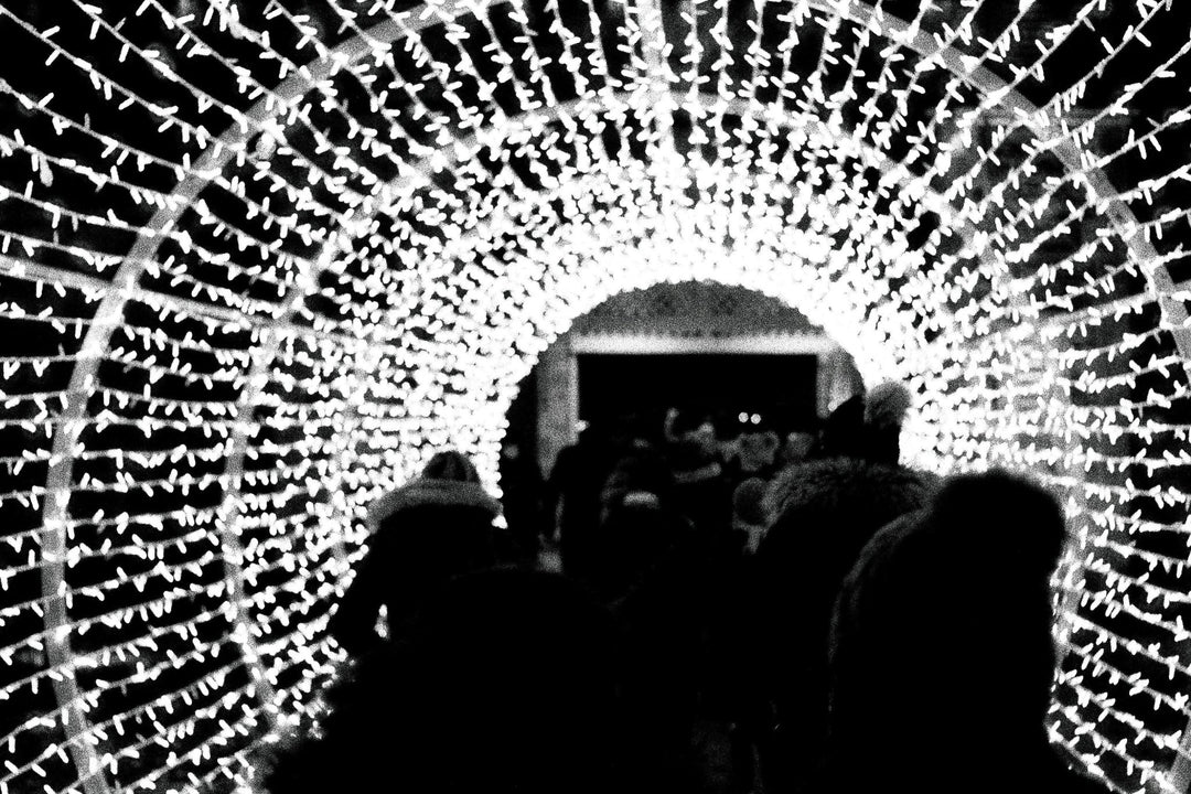 Crowd at a Christmas market photographed with Ilford Delta 3200 film, featuring bright stalls, rich shadows, and classic black and white tones.