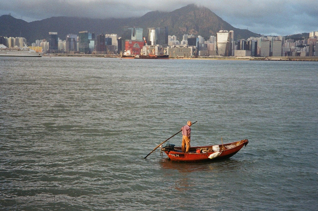 Old man paddling a small boat captured on Kodak Gold 200 35mm film, featuring vivid colours, natural skin tones, and fine detail.