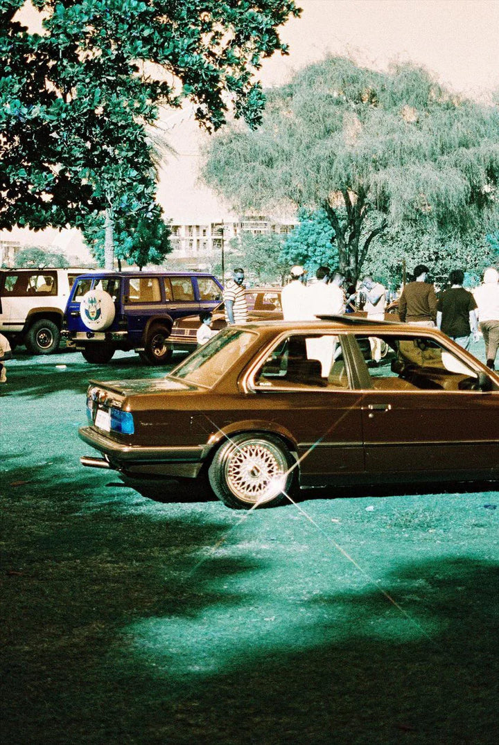 Side view of a parked car rendered in dreamy turquoise and golden tones using Lomochrome Turquoise 35mm film.