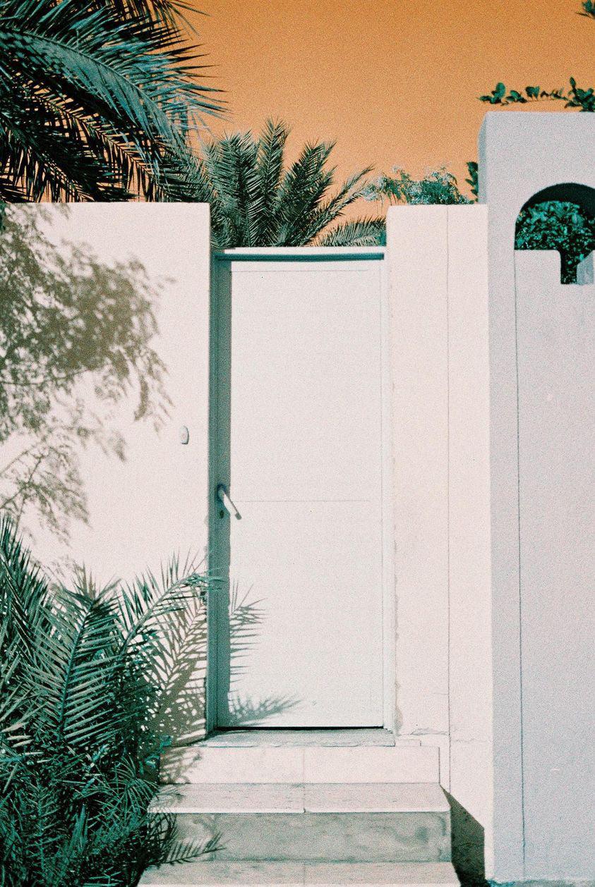 Urban street scene photographed on Lomochrome Turquoise film, with buildings and sky transformed into surreal turquoise and bronze hues.