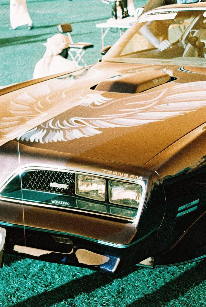 Vintage car parked under sunlight photographed on Lomochrome Turquoise 35mm film with striking turquoise highlights.