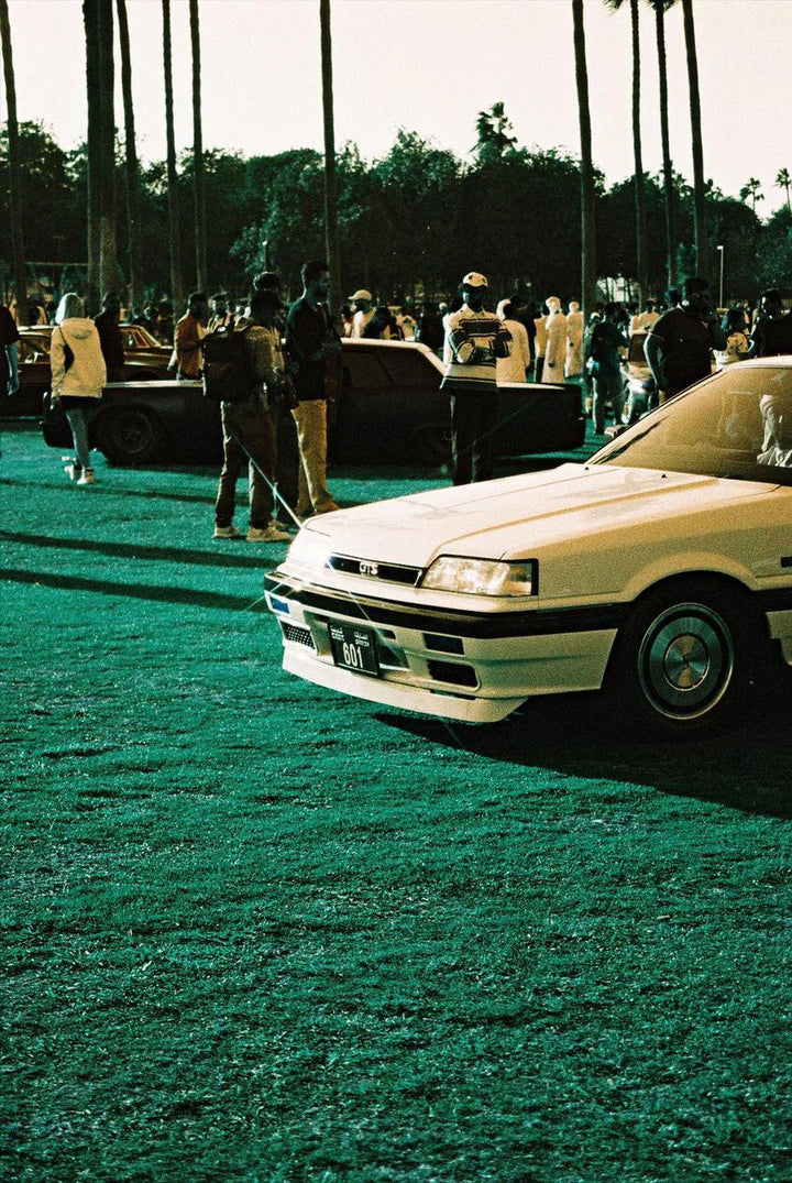 Modern car reflecting city lights shot on Lomography Lomochrome Turquoise film, featuring unique cyan and amber hues.